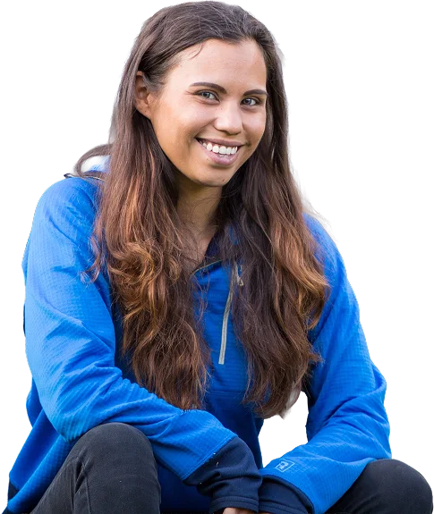 Woman with long brown hair wearing a blue outdoor jacket, smiling while seated